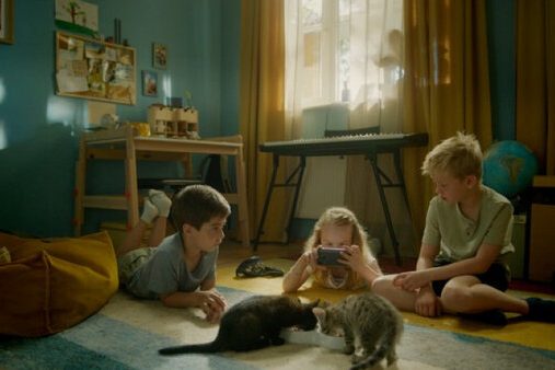 Kinder im Kinderzimmer auf dem Boden mit zwei Katzen